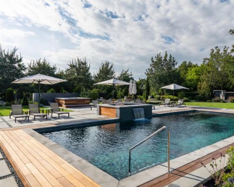 Premium rectangular pool 2026 with durable exotic wood decking, recycled natural stone coping, integrated waterfall, and crystal-clear water thanks to eco-friendly filtration—a symbol of the return to quality materials in France.