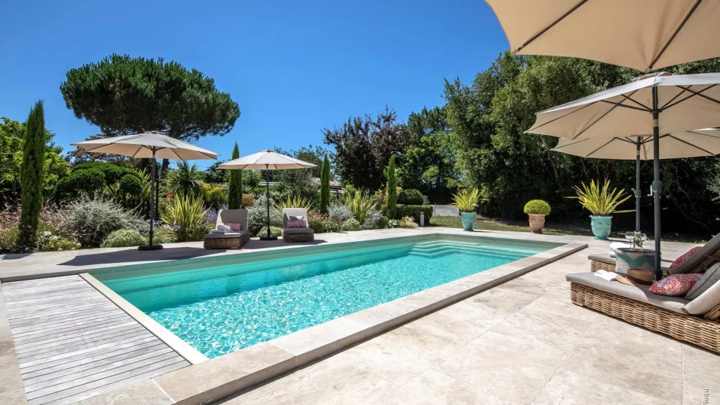 Ibiza rectangular fiberglass pool (Riviera 4 model) with natural stone pavers and Mediterranean landscaping.