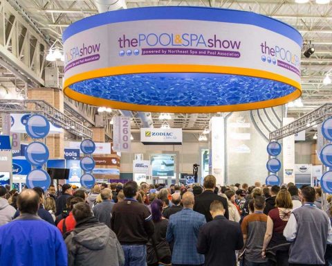 Professional visitors walking through the POOL AND SPA SHOW aisles with prominent signage for Zodiac and Pentair