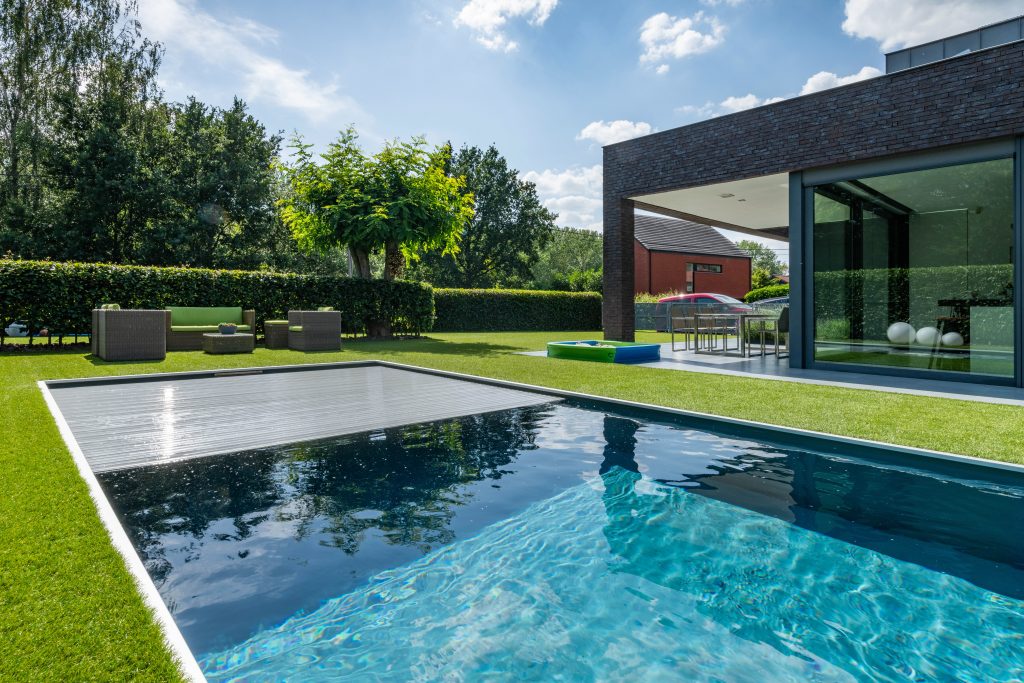 Automatische Poolabdeckung integriert in den modernen Hausgarten.