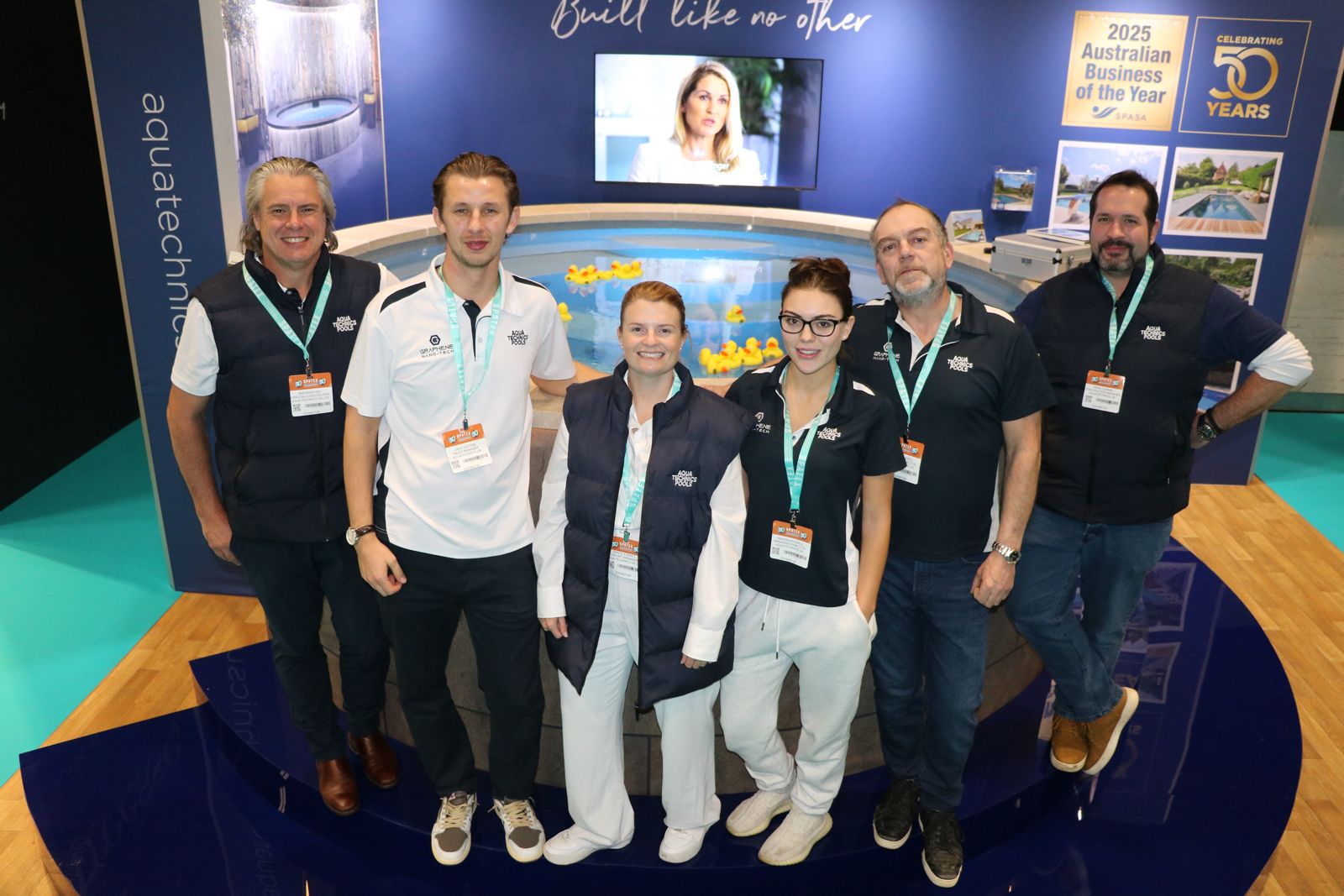 Das Aqua Technics Pools Team steht an ihrem SPATEX-Stand und feiert 50 Jahre Innovation mit Grace Everitt.