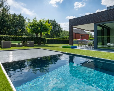 Automatischer Poolabdeckung in den Garten eines modernen Hauses integriert.