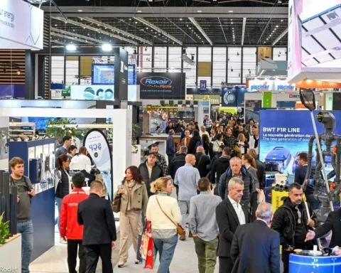 Weitläufige Panoramasicht auf die Hauptausstellungshalle der Piscine Global Messe in Eurexpo Lyon, mit überfüllten Gängen, mehreren modernen Ständen für Pool- und Spa-Aussteller, Fachleute beim Networking und Umhergehen, dynamische Atmosphäre der internationalen Pool-, Spa- und Wellnessbranche.
