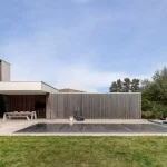 Couverture de piscine à lames automatique Aquadeck entièrement déployée sur une piscine creusée contemporaine de luxe, intégrée harmonieusement à une architecture moderne aux lignes épurées, terrasse et design haut de gamme, mettant en valeur l'efficacité énergétique, la sécurité, la durabilité et l'esthétique pour les professionnels de la construction de piscines.