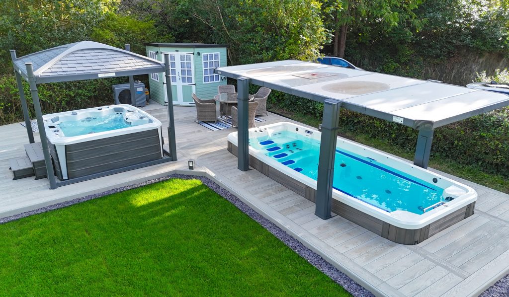 An outdoor patio area with a covered swim spa and a separate hot tub under a pergola.