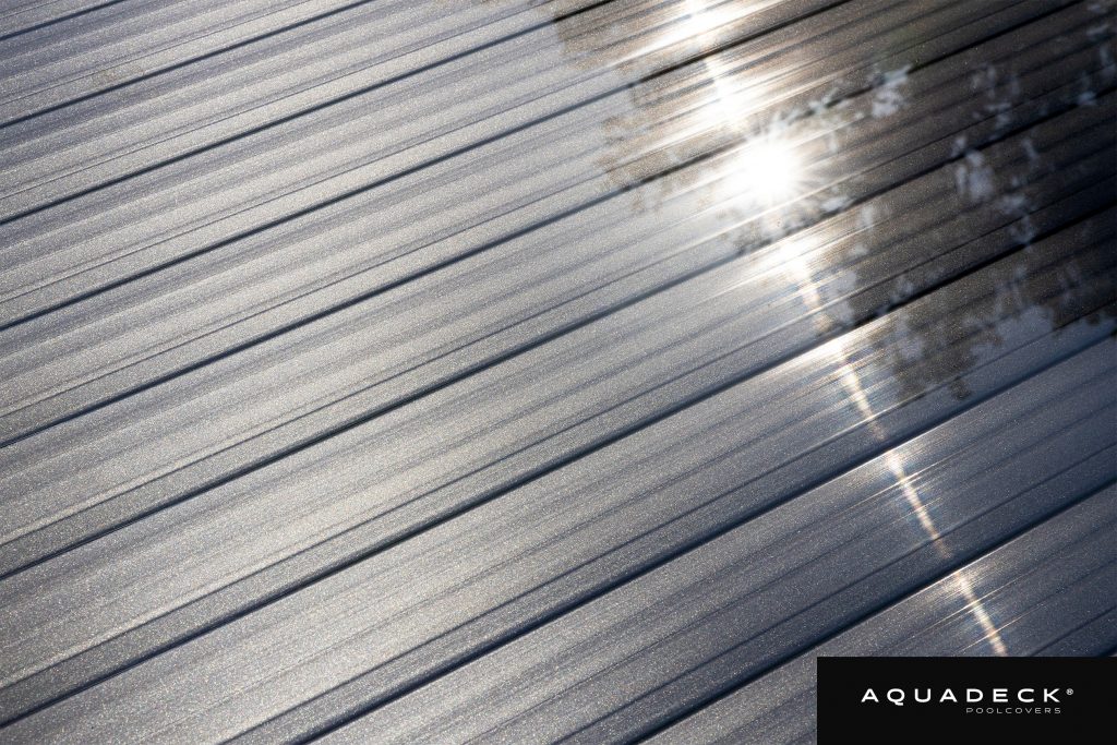 Nahaufnahme von schimmernden Aquadeck-Poolabdecklamellen mit integrierter Anti-Algen-Technologie und UV-Schutz.