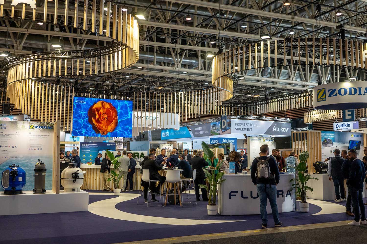 Panoramablick auf die lebhafte Ausstellungshalle bei der Piscine Global Europe 2022 in Eurexpo Lyon, organisiert von GL events, mit überfüllten Gängen, mehreren Ausstellerständen für Pools und Spas (Sorodist, Cei, Teleco, Pool Arena), Fachleuten beim Networking und Gehen, dynamische Atmosphäre der internationalen Messe für Pools, Spas und Wellness.
