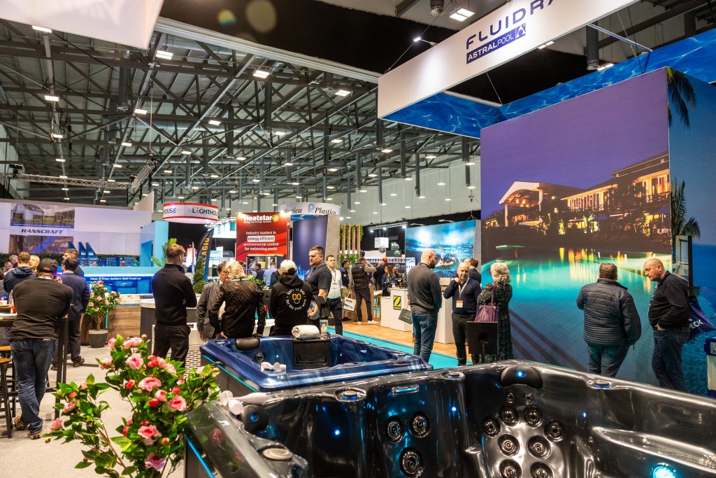 Eine lebendige Präsentation der neuesten Whirlpools und Wellnesslösungen am Stand von Fluidra und AstralPool während SPATEX 2026. Das Bild fängt die moderne Ästhetik und die "Feel Good"-Atmosphäre ein, die die 30-Jahres-Jubiläums-Ausstellungsebene prägten.