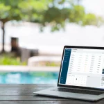 A laptop on a wooden table by a swimming pool with the MY PPG dashboard open on the screen.