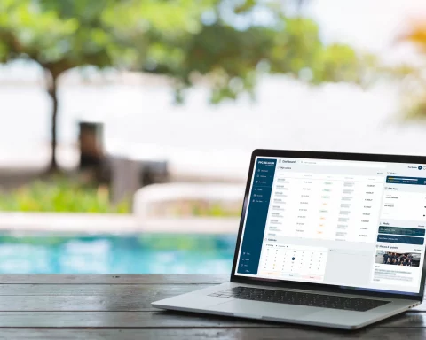A laptop on a wooden table by a swimming pool with the MY PPG dashboard open on the screen.