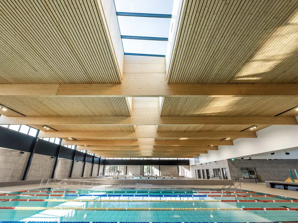Modern eco-friendly public swimming pool with sustainable wood architecture.