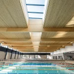 Modern eco-friendly public swimming pool with sustainable wood architecture.