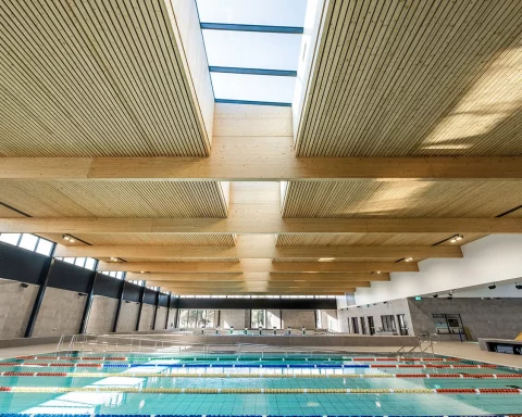 Modern eco-friendly public swimming pool with sustainable wood architecture.