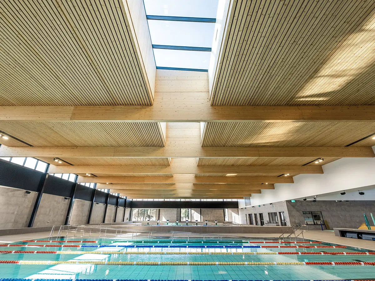 Modern eco-friendly public swimming pool with sustainable wood architecture.
