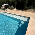 Submerged WaluRoll UR800 automatic pool cover by Walter Pool installed in a luxury villa with a stone terrace.