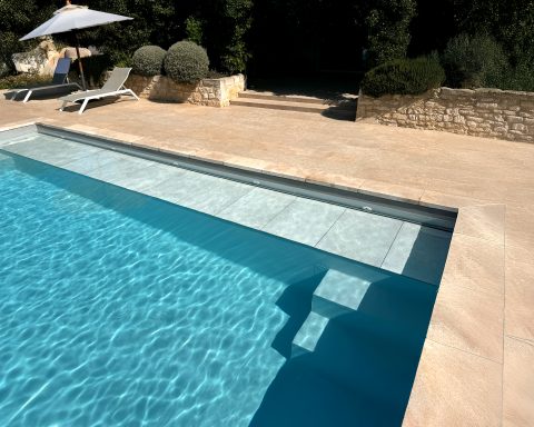 Submerged WaluRoll UR800 automatic pool cover by Walter Pool installed in a luxury villa with a stone terrace.