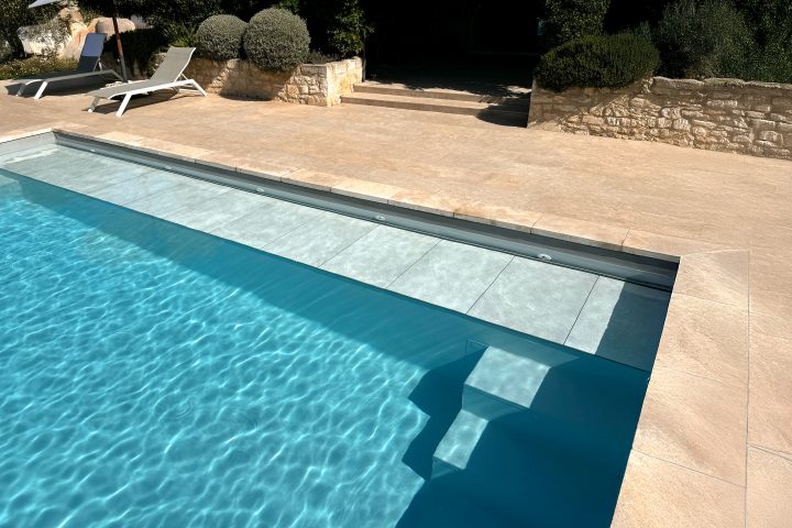 Submerged WaluRoll UR800 automatic pool cover by Walter Pool installed in a luxury villa with a stone terrace.