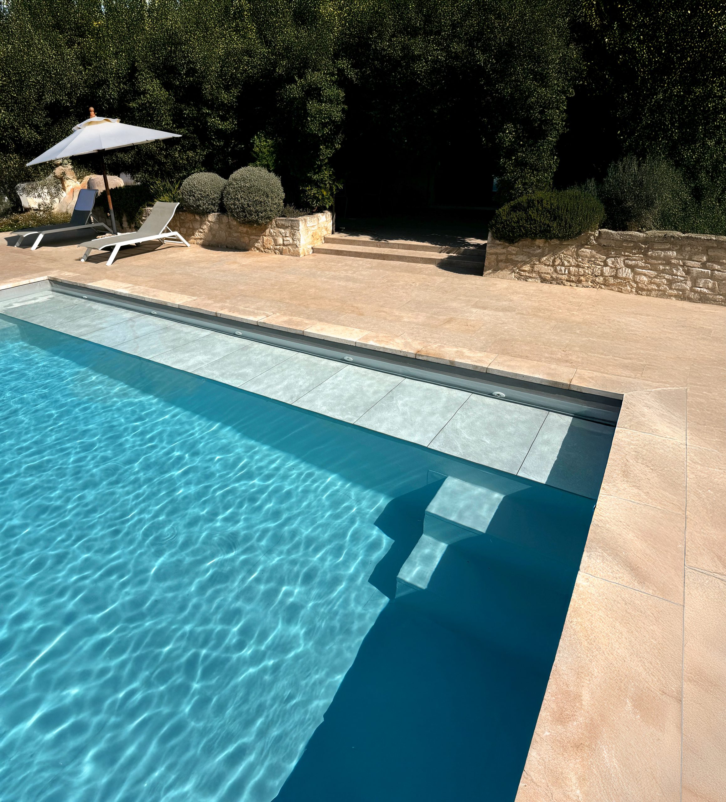 Submerged WaluRoll UR800 automatic pool cover by Walter Pool installed in a luxury villa with a stone terrace.