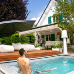 Man relaxing in a small, modern urban pool next to a raised wooden WaluDeck Flat mobile deck by Walter Pool.