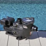 Hayward TriStar VSTD variable speed pool pump installed on a deck next to a swimming pool.