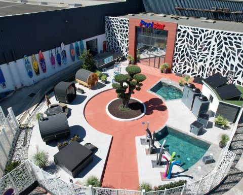 Vue aérienne du showroom extérieur de Poolstar avec piscine, saunas et paddles colorés.