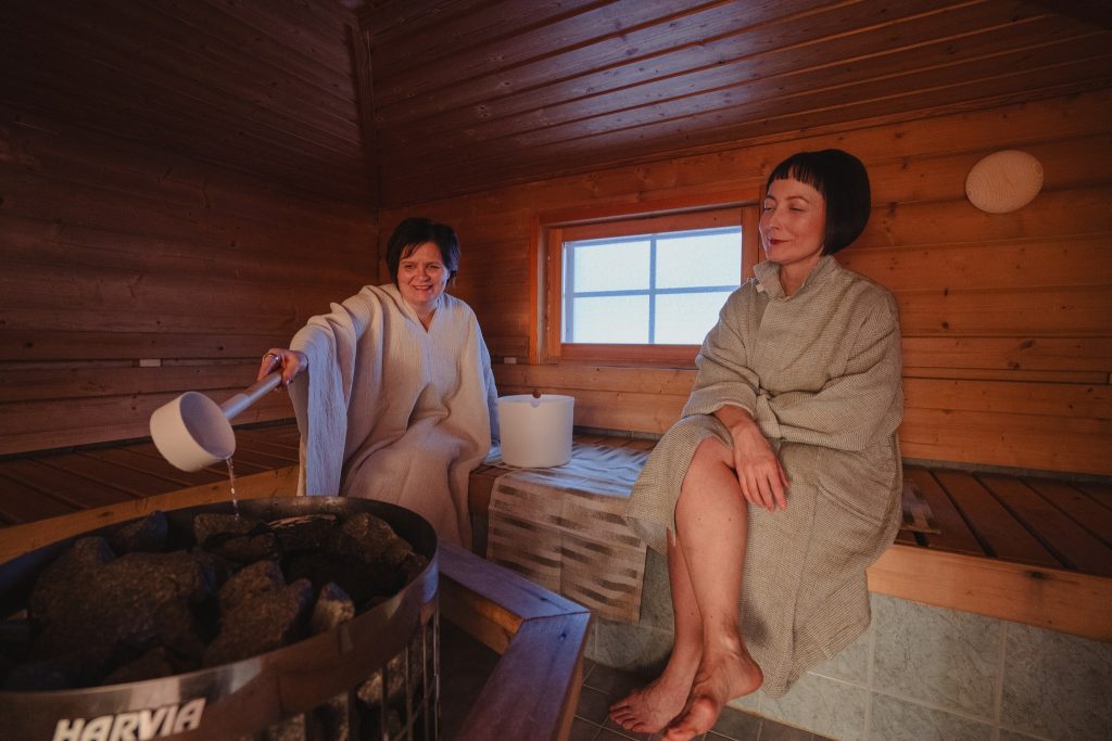 People enjoying a social sauna session in a modern dome-shaped sauna with a view of nature.