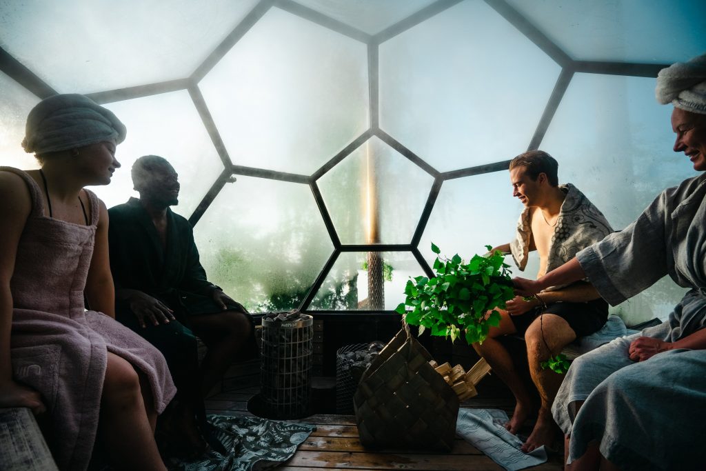 People enjoying a social sauna session in a modern dome-shaped sauna with a view of nature.