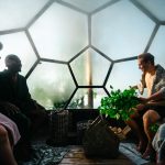 People enjoying a social sauna session in a modern dome-shaped sauna with a view of nature.