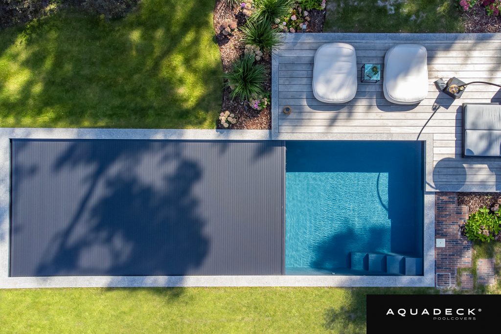 Aquadeck automatic slatted pool cover integrated into a modern luxury swimming pool
