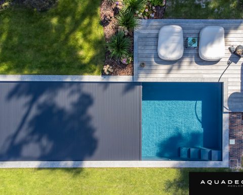 Aquadeck automatic slatted pool cover integrated into a modern luxury swimming pool