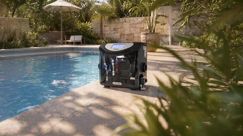 A Poolex Aqualyser automated water treatment and dosing unit placed horizontally on the stone edge of a sunny residential swimming pool.