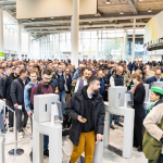 Crowd of professional visitors passing through entrance gates at Koelnmesse during Aquanale pool and spa trade show