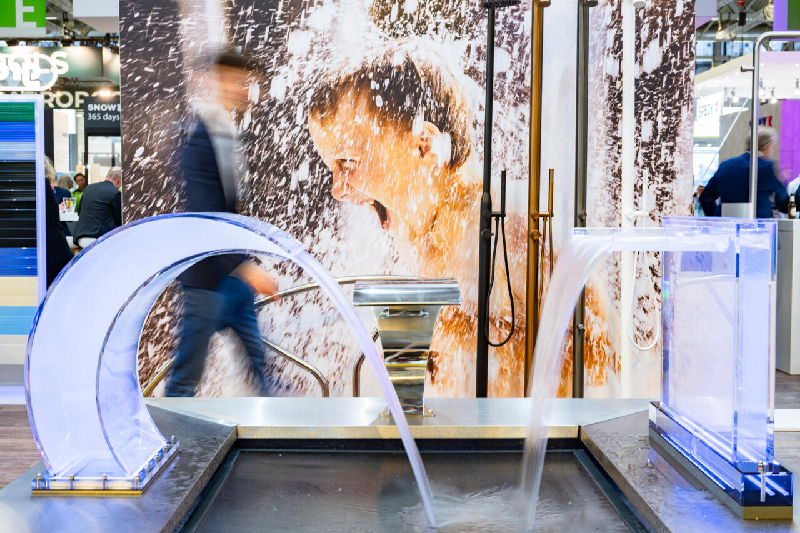 Indoor water feature display with cascade fountain and shower equipment at Aquanale pool and spa trade show