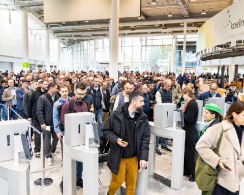 Crowd of professional visitors passing through entrance gates at Koelnmesse during Aquanale pool and spa trade show