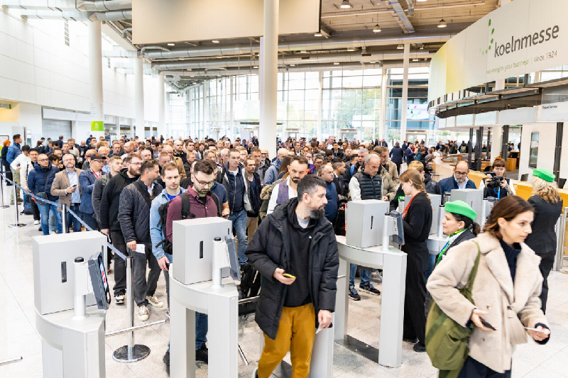 Crowd of professional visitors passing through entrance gates at Koelnmesse during Aquanale pool and spa trade show