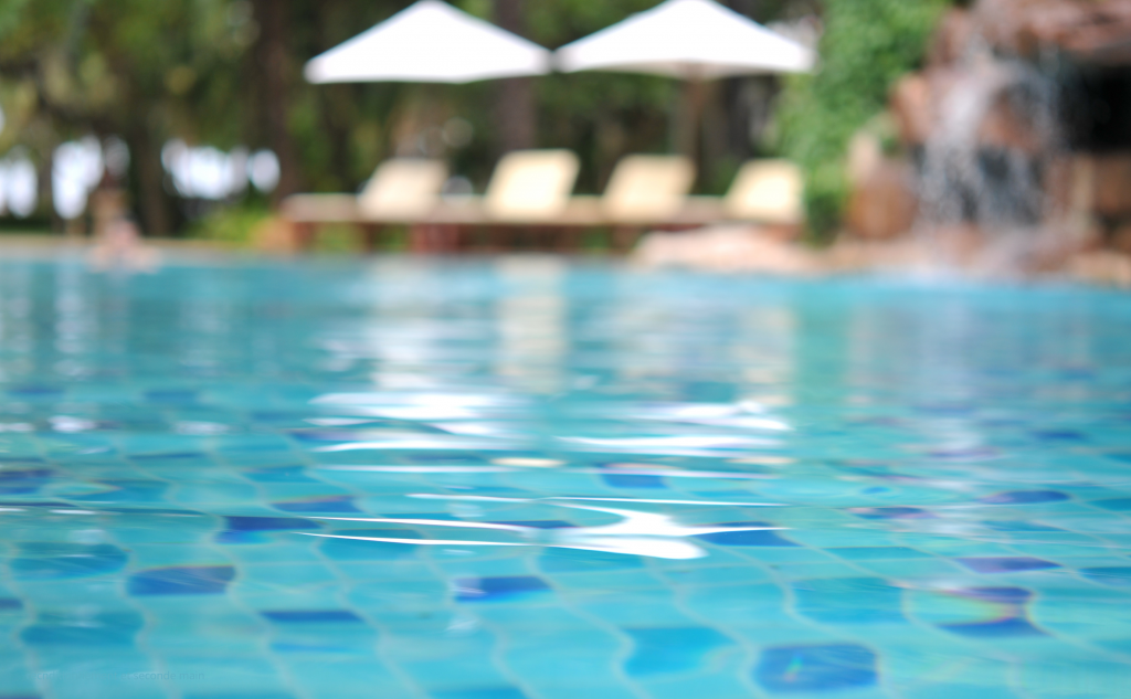 Blurred swimming pool with clear blue water illustrating sustainable pool maintenance and refurbished pool equipment