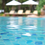 Blurred swimming pool with clear blue water illustrating sustainable pool maintenance and refurbished pool equipment