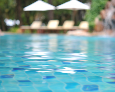 Blurred swimming pool with clear blue water illustrating sustainable pool maintenance and refurbished pool equipment