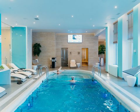 A large, modern indoor commercial tiled spa with hydrotherapy water jets in a luxury hotel wellness area.