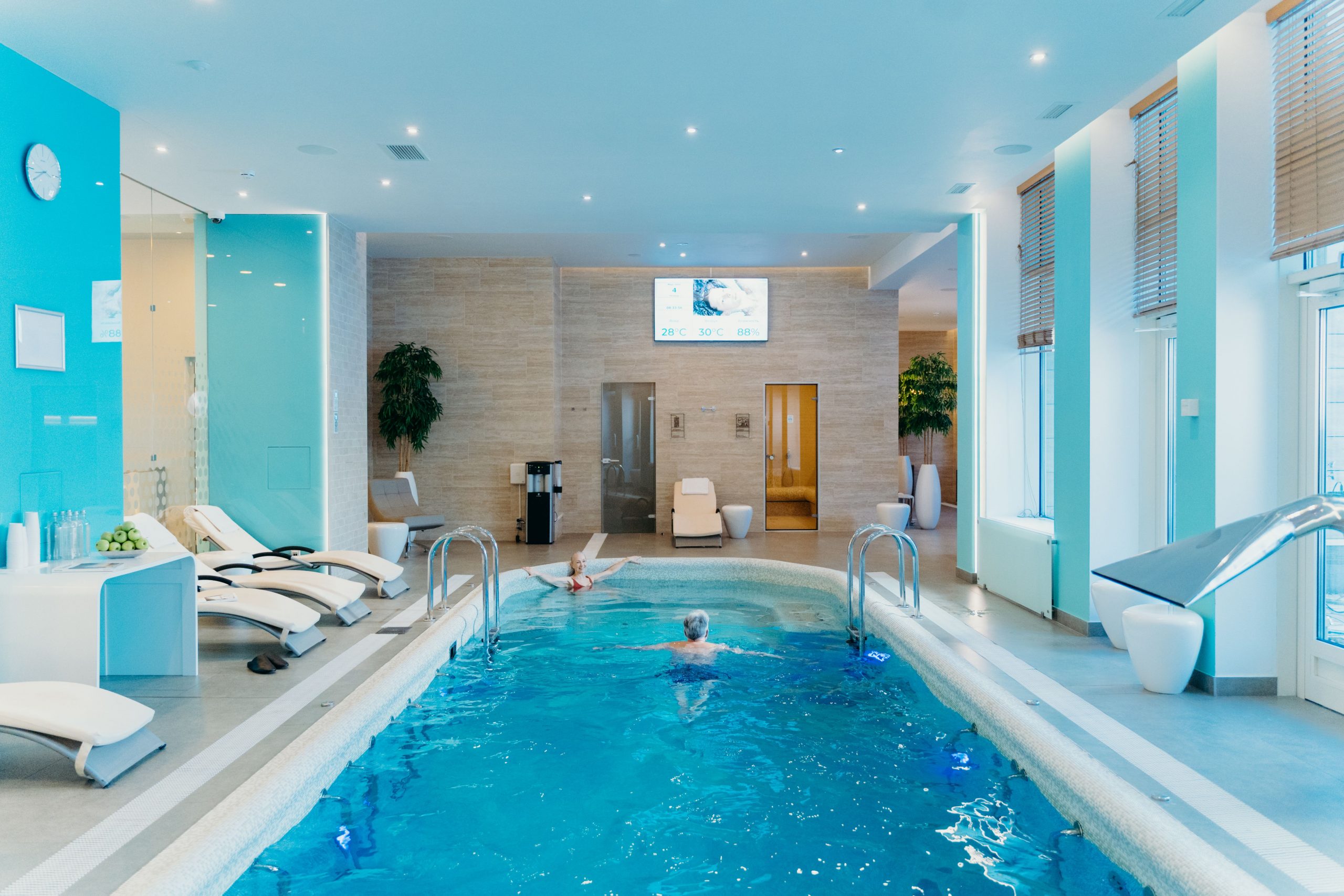 A large, modern indoor commercial tiled spa with hydrotherapy water jets in a luxury hotel wellness area.