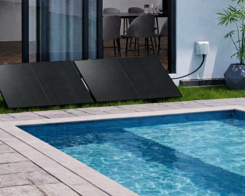 Poolex Plug and Play solar kit with two photovoltaic panels installed on the lawn next to a swimming pool