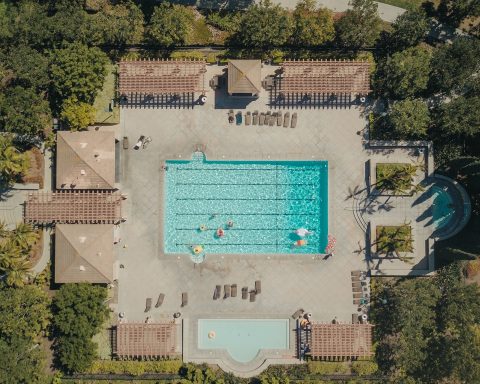 Directly overhead aerial drone photograph of a swimming pool complex and property surrounded by trees