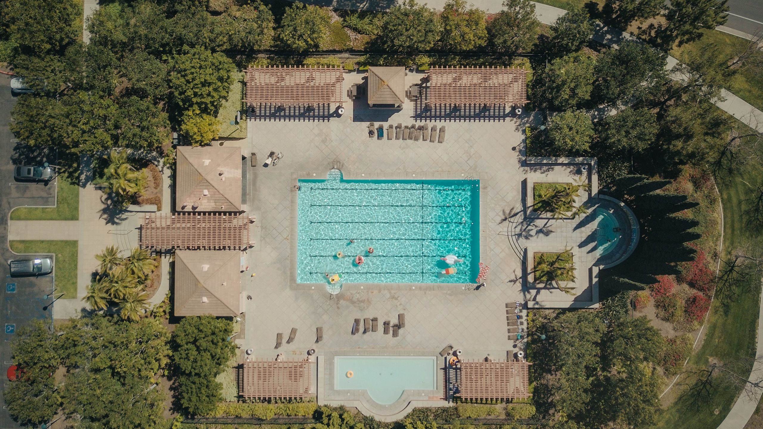 Directly overhead aerial drone photograph of a swimming pool complex and property surrounded by trees