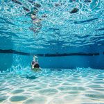 Young boy swimming underwater in a crystal clear residential swimming pool during summer