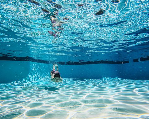 Young boy swimming underwater in a crystal clear residential swimming pool during summer