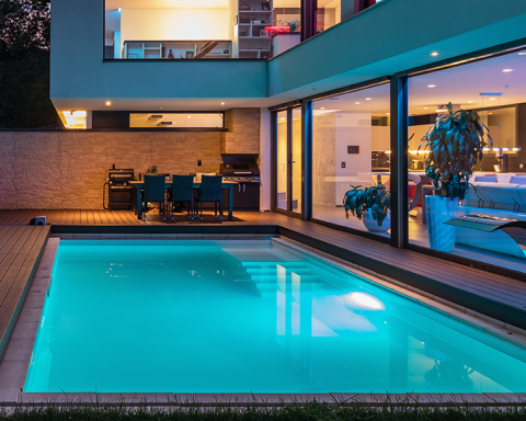 Inground pool illuminated at night with SEAMAID LED spotlights and stylish deck area