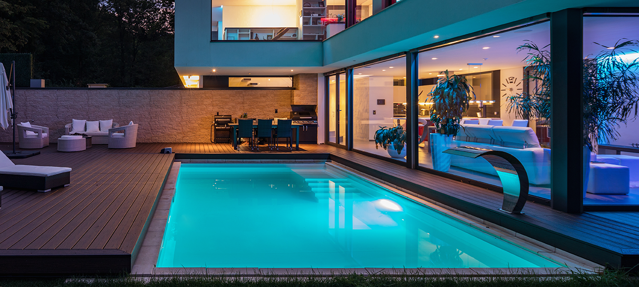 Inground pool illuminated at night with SEAMAID LED spotlights and stylish deck area