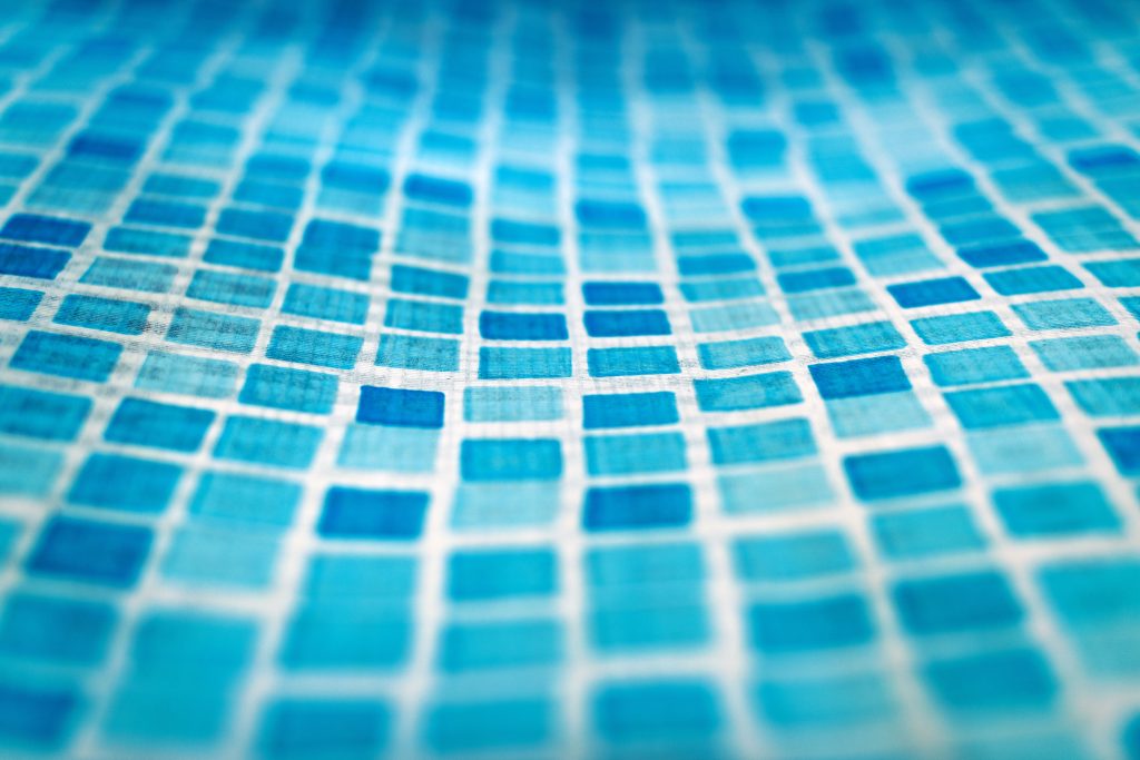 Detailed close-up of a blue mosaic pattern on a swimming pool liner membrane.