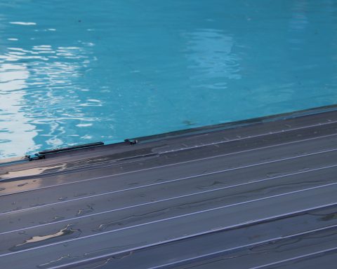 DeckLine X320™ automatic pool cover slatted structure by APF Pool Design deployed on a swimming pool.