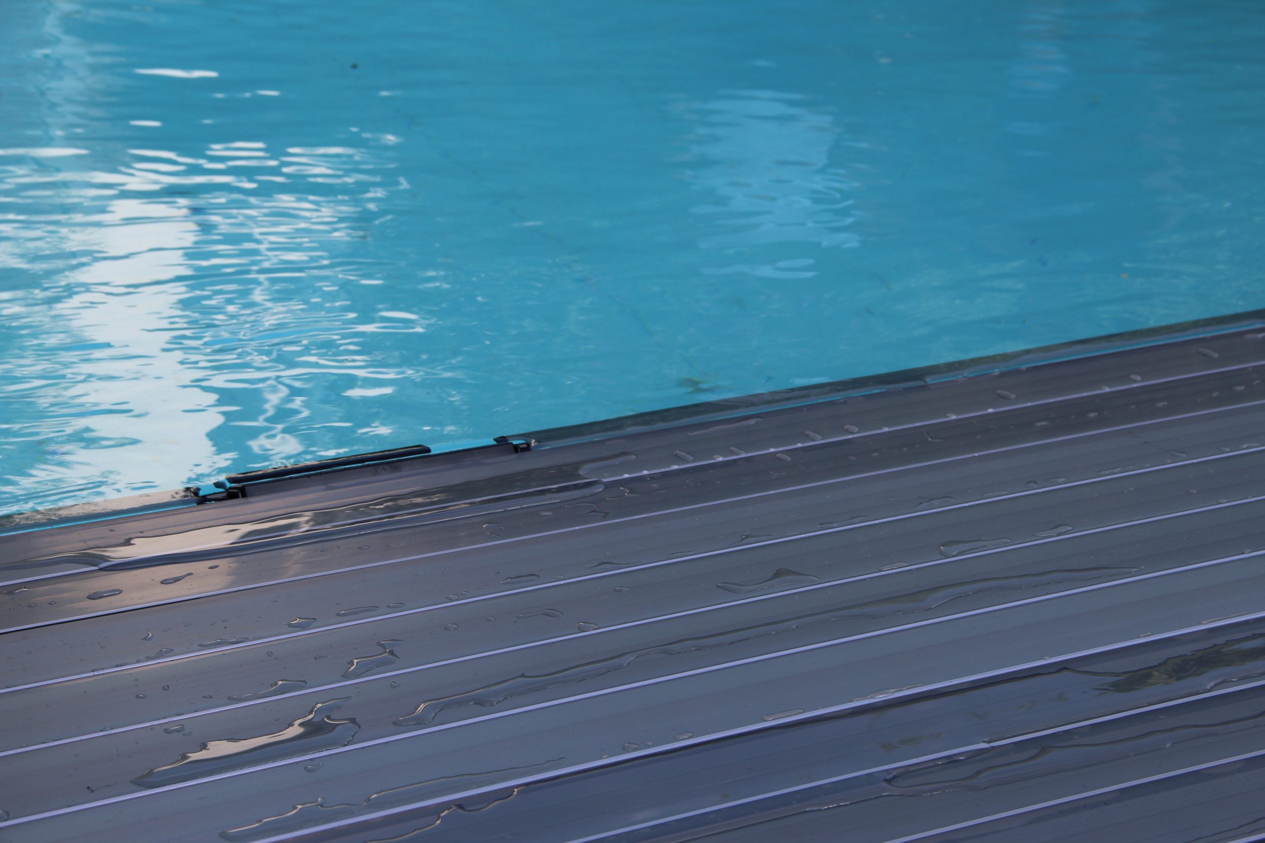 DeckLine X320™ automatic pool cover slatted structure by APF Pool Design deployed on a swimming pool.